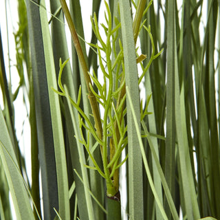 Detail shot of the artificial plant showing bright green, branching foliage among varied grass blades.