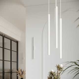 White wall lamp paired with three matching cylindrical pendant lights in a modern interior.