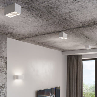 Three quad lights mounted on a textured concrete ceiling and a white wall in a contemporary interior.