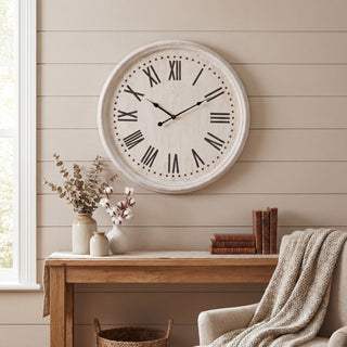 White wash wall clock featuring black Roman numerals, shown in a styled interior above a wooden console table.