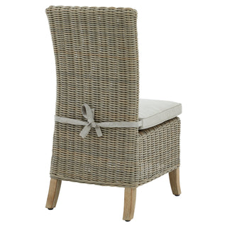 Back view of the tall wicker dining chair with a beige cushion secured by a fabric bow tie.