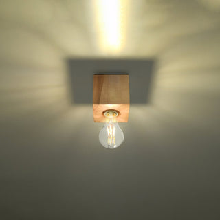 Warm light cast upwards onto the ceiling by the wooden lamp base, showing the square shadow outline.