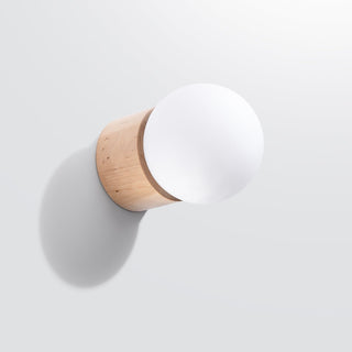 Angled shot showing the light wood base and large white glass globe casting a shadow on the white wall.