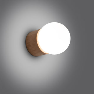 Close-up of the wooden lamp base and bright white globe shade illuminating the dark grey wall.