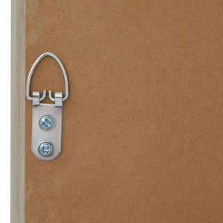 Close-up of the silver D-ring picture hanger attached to the brown backing board on the rear of the wooden frame.
