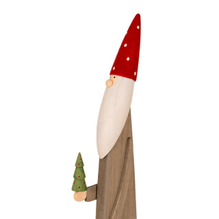 Three-quarter view of the wooden elf decoration, showing the long red spotted hat, painted face, and the small green tree.