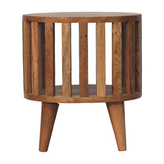 Low-angle view of the round wooden bedside table highlighting the internal shelf and three tapered legs.