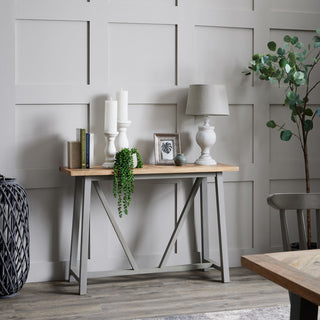 Table lamp on a grey console table against a panelled wall, surrounded by decorative accessories.